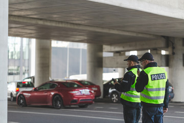 Police officers in black uniforms and yellow vests standing on the parking lot