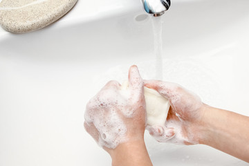 A Hands with soap are washed under the tap with water. Clean from infection and dirt and virus. At home or in the hospital ablution office.