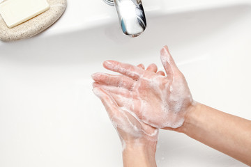 Fototapeta premium A Hands with soap are washed under the tap with water. Clean from infection and dirt and virus. At home or in the hospital ablution office.