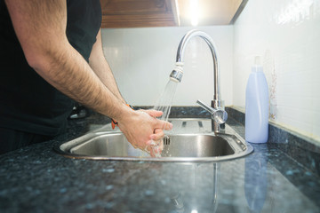 Unknown man cleaning his hands under the tap