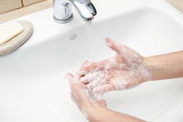 A Hands with soap are washed under the tap with water. Clean from infection and dirt and virus. At home or in the hospital ablution office.