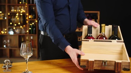 Man taking from box and opening bottle of expensive wine in cellar