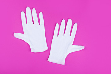 White gloves lie in a pink background.