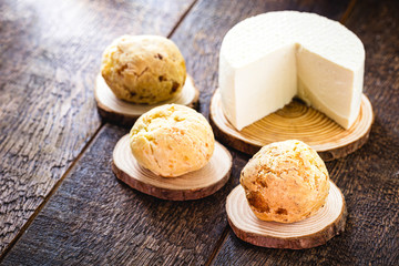 Brazilian cheese bread, hot, freshly made. Polvilho and Minas Gerais cheese in the background, on a rustic wooden box. Homemade, organic snack.