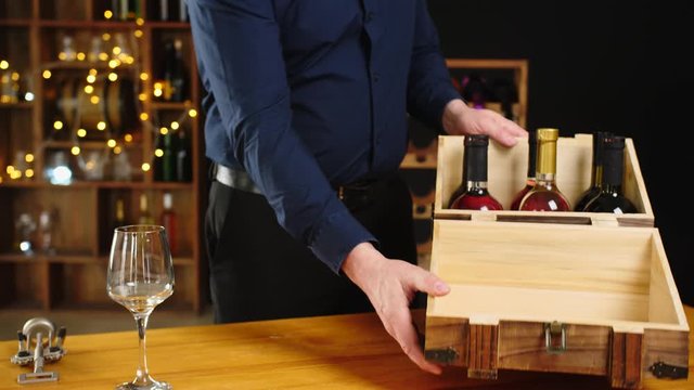 Man taking from box and opening bottle of expensive wine in cellar