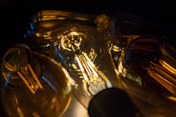 Invention, ideas and leadership concept; Close up glowing lighting bulb on dark black background.