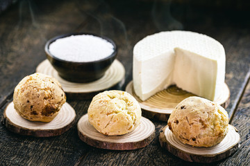 Brazilian cheese bread, hot, freshly made. Polvilho and Minas Gerais cheese in the background, on a rustic wooden box. Homemade, organic snack.