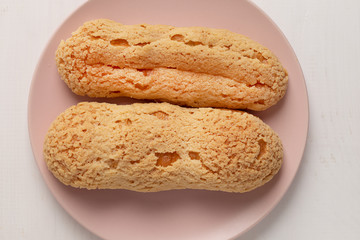 Eclair on the plate. Light pastel background. Dessert. concept, minimalism
