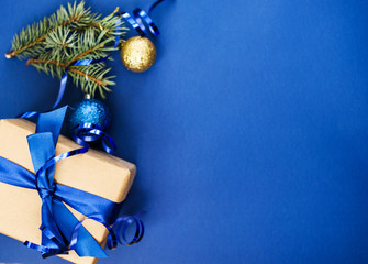 Festive New Year's content with a place for text, on a blue background a sprig of pine, a ball, a gift.