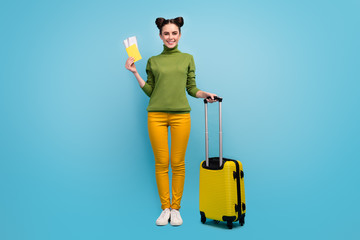 Full length photo of funny pretty lady hold tickets documents cheap tour abroad flight rolling suitcase wear green turtleneck yellow pants shoes isolated blue color background