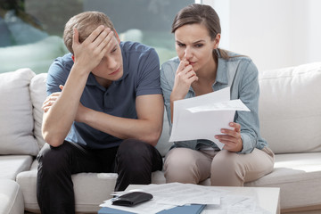 Stressed married couple looking frustrated, having no money to pay off their debts, managing family budget together