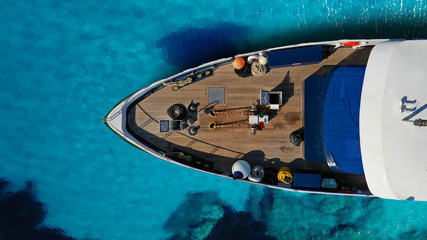 Aerial drone top down photo of luxury exotic yacht nose with wooden deck anchored in paradise turquoise bay
