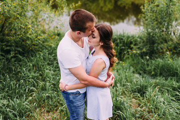 Happy young couple walks in the park, love story. The relationship of a guy and a girl, a photo shoot in nature