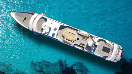 Aerial drone top down photo of luxury mega yacht anchored in tropical exotic bay with turquoise sea