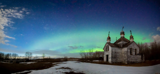 Old dilapidated Ukrainian orthodox church in small Canadian prairie locations with Northern Lights...