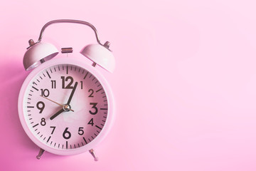 Pink alarm clock lying on pink