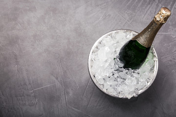 Champagne in metal bucket with ice on grey table, top view. Space for text © New Africa