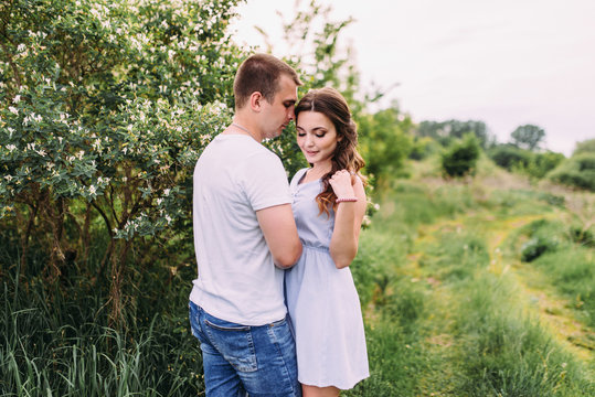 Happy young couple walks in the park, love story. The relationship of a guy and a girl, a photo shoot in nature