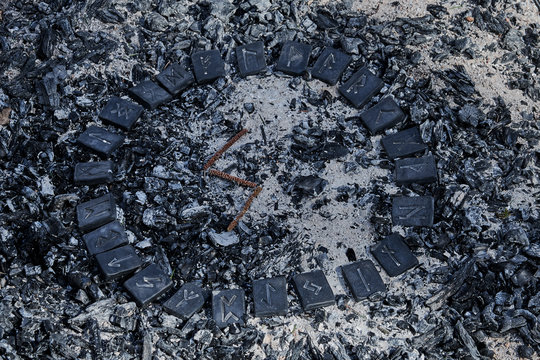 Norse rune Sowilo on ashes backgorund inside the circle of 24 Norse runes