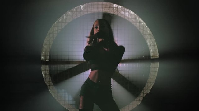 A young black woman is dancing, a fan is spinning in the background. There is smoke in the room