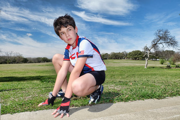 Male child cyclist kneeling outside