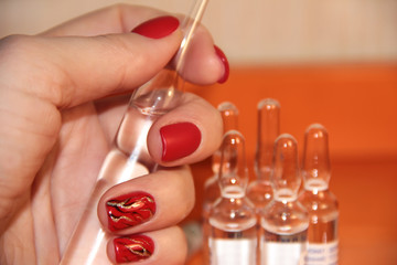 Ampoules in a woman's hand. The vaccine on an orange background.