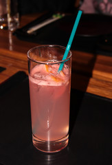 Grapefruit drink in a glass with a straw.