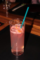 Grapefruit drink in a glass with a straw.