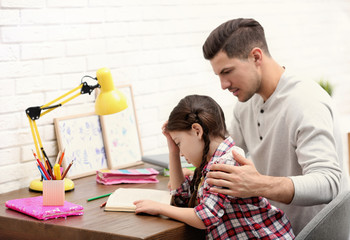 Man helping his daughter with homework at table indoors - obrazy, fototapety, plakaty