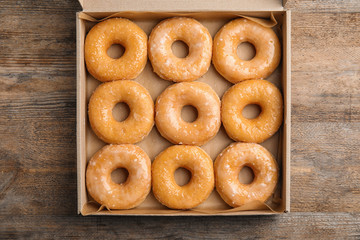 Delicious donuts on wooden table, top view