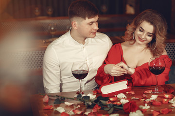 Couple in a restaurant. Lady in a red dress. Pair drinking a vine. Valentine's day.