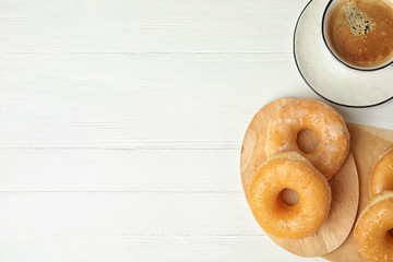 Delicious donuts and coffee on white wooden table, flat lay. Space for text