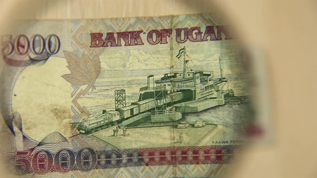 View a Five thousand Ugandan shillings bill lying on a table with a magnifying glass. concept of business and finance. reverse side