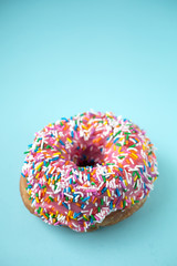 Pink donut with candies on blue background