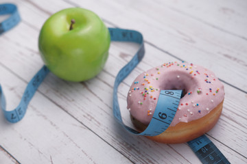 close up of apple, donut and measurement tape on table
