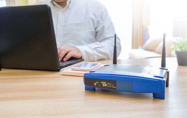 closeup of a wireless router and a man using computer on living room at home ofiice, man working...