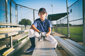 Male child baseball player sitting on bleachers
