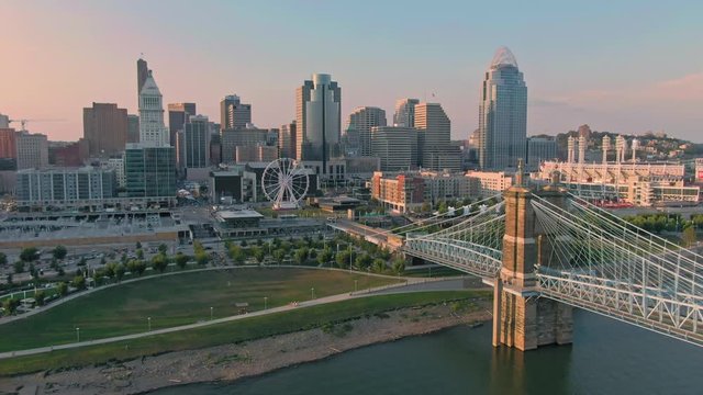 Aerial: Downtown Cincinnati and the John A. Roebling Suspension Bridge on the Ohio River at sunrise. Cincinnati, Ohio, USA. 21 September 2019