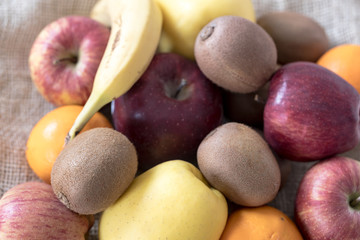 fruits and vegetables, bananas apples and oranges and kiwis on a jute