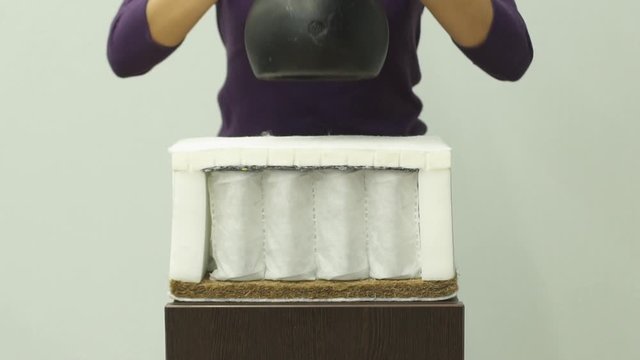 Woman puts a heavy weight on an orthopedic foam mattress slow motion