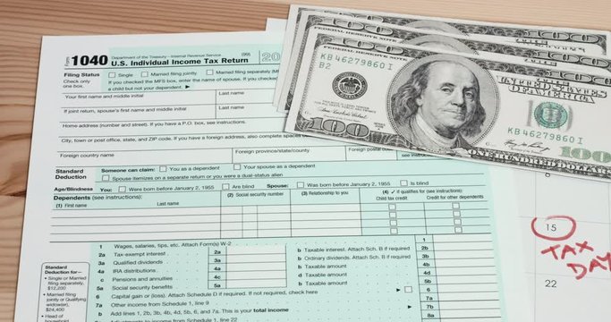US 1040 tax day return form with 100 usd dollar bills and calendar