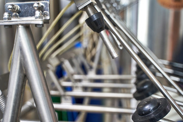 Metal pipettes in a row connected to bottle-filling machines