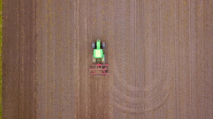 Traktor mit Pflug bei der Bodenbearbeitung eines Ackers aus der Vogelperspektive