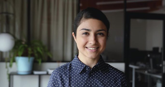 Smiling confident young indian ethnic business woman professional looking at camera standing alone at home office. Happy pretty millennial businesswoman, student, worker, close up face portrait