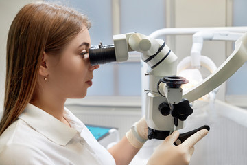 Doctor woman with microscope, young girl medic studies on a microscope, virus, laboratory
