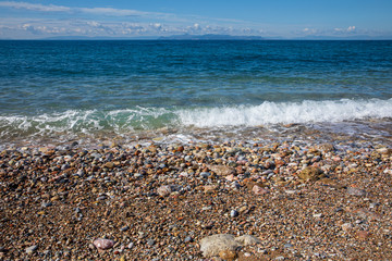 Beautiful seascape with calm sea, pebbles beach, blue sky of suburb in South Athens located in the Athens Riviera, Greece.