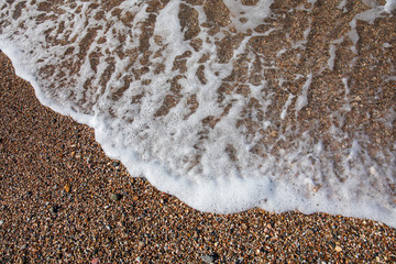 Sea wave rolls on the pebbles beach of suburb in South Athens located in the Athens Riviera, Greece.