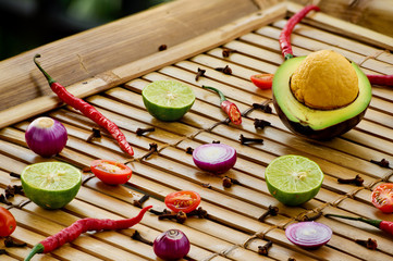 Culinary background. Pattern of fresh vegetables and spices on the bamboo wooden background. Ingredients for sauce guacamole.