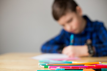 Blurred with copy space. Cute boy learning at home during covid-19 coronavirus quarantine.