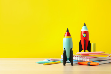 Bright toy rockets and school supplies on wooden table. Space for text